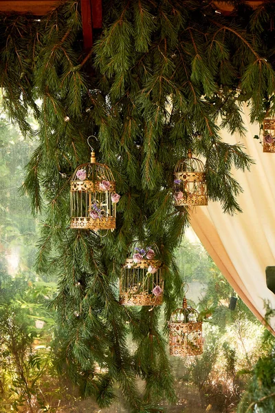 結婚式の装飾花のある黄金のケージは、トウヒの葉にかかっています。エコデザイン. — ストック写真