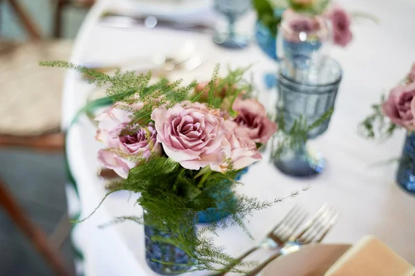 Küçük mavi vazolarda toz güller. Düğün dekoru ya da romantik randevu tasarımı. Çiçek..