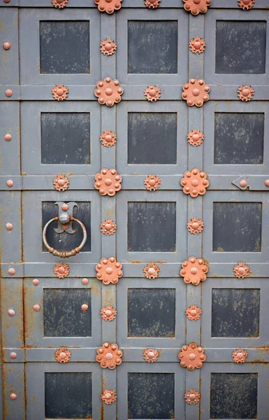 Una porta in metallo con maniglia rotonda.Una vecchia porta decorata con elementi forgiati. — Foto Stock