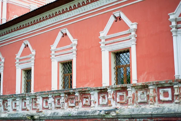 Бледная красная стена русской церкви с белыми окнами и металлическими решетками.. — стоковое фото