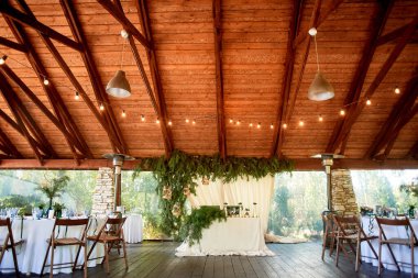 Açık havada, ahşap tavanlı bir ziyafet salonu, asılı çelenkler. Çevre tasarımı..