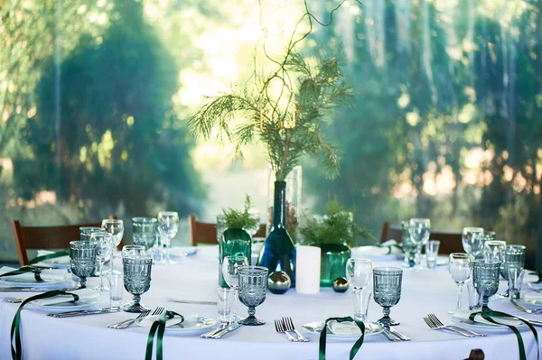 Restaurant design.A table covered with a white tablecloth, a classic serving. Bottles of blue and green glass. Paws ate. — Stock Photo, Image