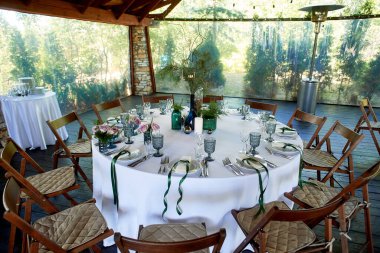 Restoranda dekorasyonla süslenmiş bir masa, patileriyle yenmiş renkli şişeler. Ahşap ve taştan yapılmış açık bir veranda. Isı silahı..