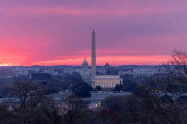 Lincoln Anıtı, Washington Anıtı ve Capitol silueti ile Washington, D.C. üzerinde gün doğumu canlı pembe ve mor bir gökyüzüne karşı..