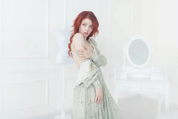 一个年轻的梦幻般的红头发的女人穿着漂亮的复古礼服的肖像 她穿着赤裸的乳房站在更衣室里 — 图库照片