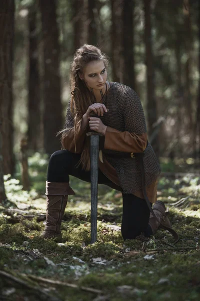 Viking kadın kılıçla geleneksel savaşçı kıyafetlerle derin gizemli bir ormanda