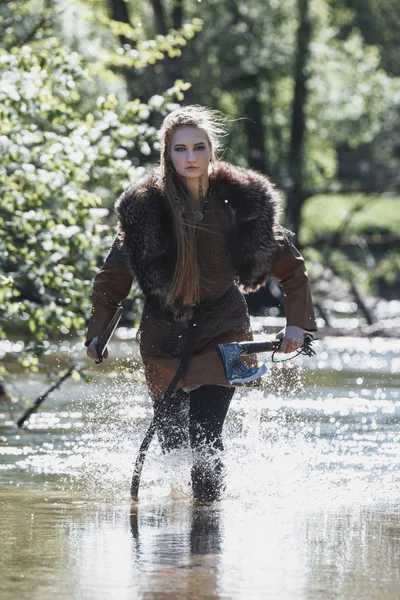 Viking kadın kılıç ve geleneksel savaşçı kıyafetlerle derin gizemli bir ormanda çekiç