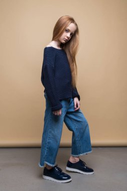 Güzel genç Kızıl saçlı kız kot pantolon ve kazak stüdyo çekim