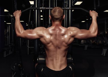 Sırt kasları kadar pompalama yakışıklı güçlü atletik bir adam. Spor salonunda egzersizleri yapıyor çıplak spor gövde ile kas vücut geliştirmeci
