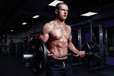 Halter salonunda ile egzersizleri yapıyor atletik genç adam. Yakışıklı kaslı vücut geliştirmeci adam gidiyor