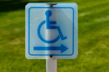 Tekerlekli sandalye sembolü ve sağı gösteren bir ok ile bulanık yeşil bir arka plan..