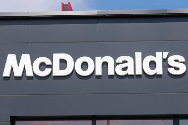 Arka planda mavi gökyüzü olan gri bir binaya yakın çekim McDonald 's tabelası..