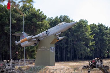 Gri bir F-104 Starfighter jeti zeytin yeşili bir kaideye monte edilmiştir. Uçaksavar silahları ön planda sergileniyor..