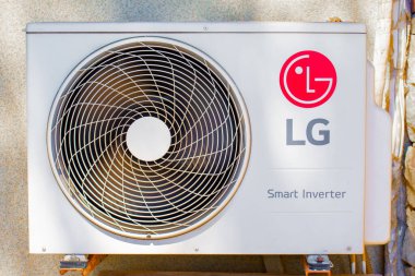 Açık havada bir LG klima ünitesinin yakın çekimi, vantilatörü, konutu, logoyu ve 