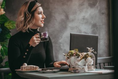 Dizüstü bilgisayar ve içecek kahve yazarak kız