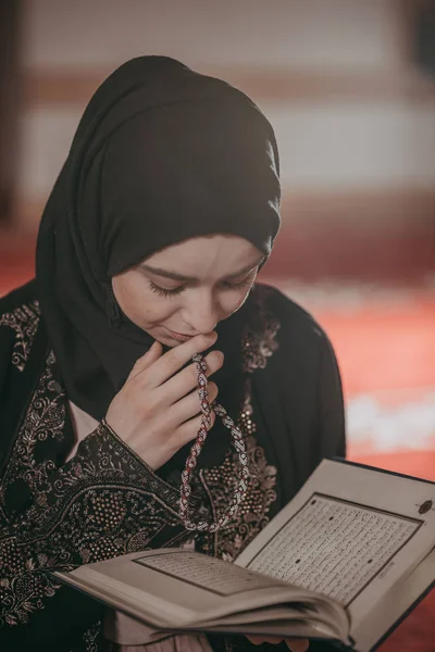 Young muslim girl reading a holy book