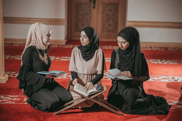 Three muslim girls reading Quran in mosque