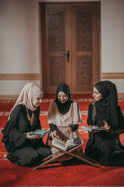 Three muslim girls reading Quran in mosque