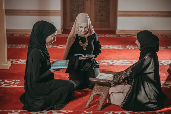 Three muslim girls reading Quran in mosque