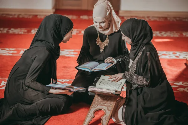 Three muslim girls reading Quran in mosque