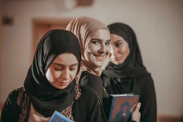 Three muslim girls reading Quran in mosque