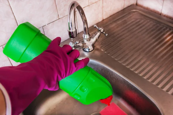 Nainen siivoaa pesuallasta kemikaaleilla. . — kuvapankkivalokuva