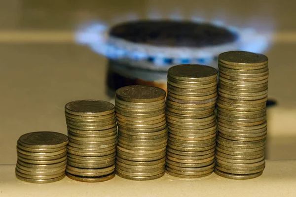 Gaz fiyat kavramında artış. Mavi gaz alev ve sikke artan yığını.