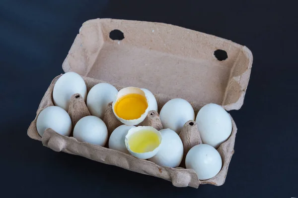 White eggs and one broken egg in the carton box with mockup to text.