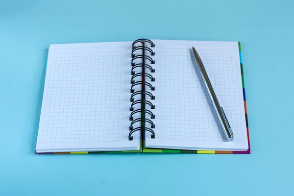 Ανοίξτε το κενό σημειωματάριο και ένα ασημένιο στυλό ως ένα mockup κείμενο σε παστέλ χρώμα φόντου. — Φωτογραφία Αρχείου