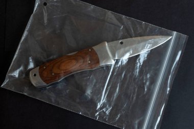 Knife in a plastic package on black color background table. clipart