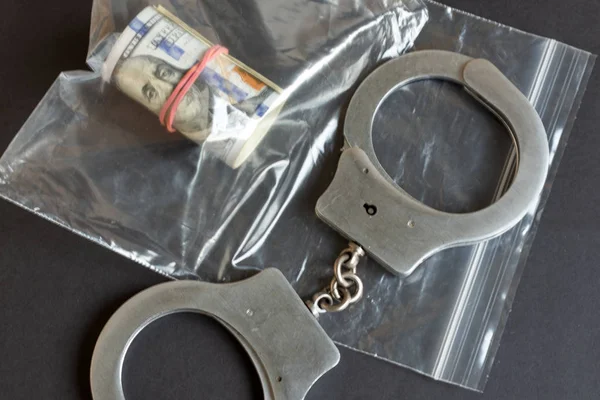 Currency in a plastic package and handcuffs. — Stock Photo, Image