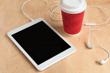 Tablet ile kulaklık ile boş siyah perde ve bir fincan kahve üst görüntüleme.