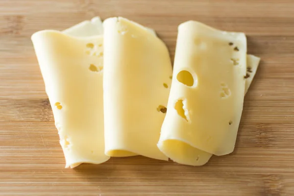 Fatias de queijo no fundo de madeira . — Fotografia de Stock