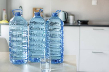 Parlak mutfak backgroung üzerinde masada su ile büyük plastik şişe.
