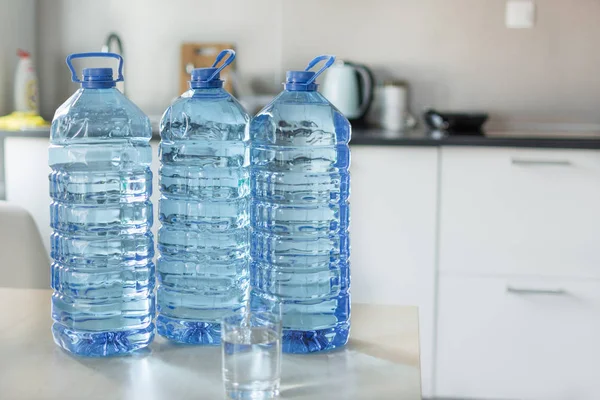 Parlak mutfak backgroung üzerinde masada su ile büyük plastik şişe.