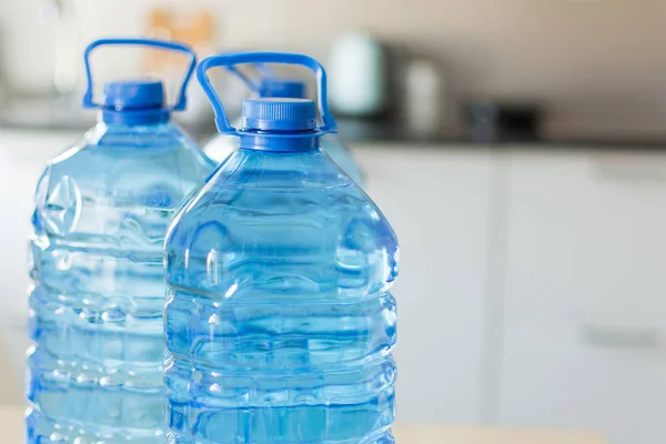 Parlak mutfak backgroung üzerinde masada su ile büyük plastik şişe.