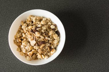 Yulaf gevreği veya granola fındık, kuru meyve ve siyah taş masada çilek ile.
