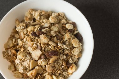 Yulaf gevreği veya granola fındık, kuru meyve ve siyah taş masada çilek ile.