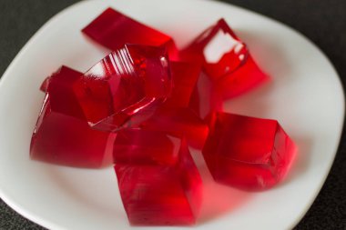 Beyaz plaka arka planda kırmızı jöle küpleri.