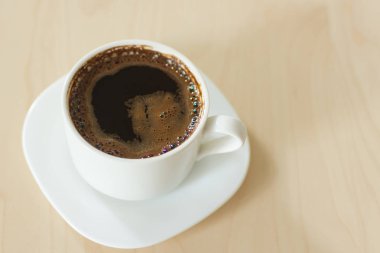 Kahve fincanı ve çay tabağı ahşap bir masada..