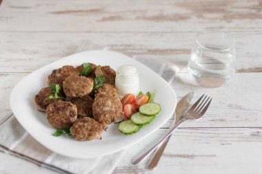 Hafif ahşap bir masa üzerinde beyaz bir tabak sulu lezzetli et pirzola.