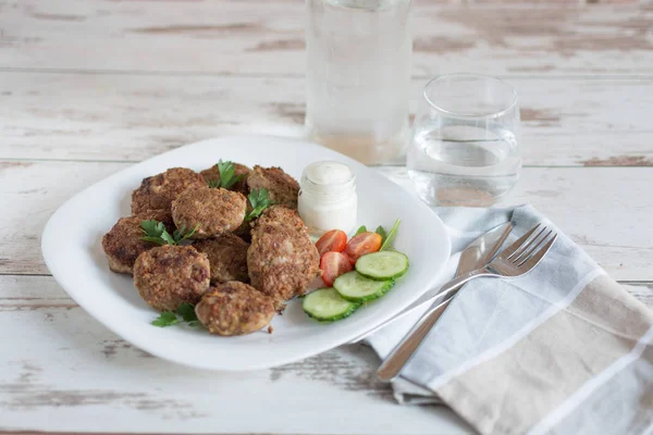 Saftige, köstliche Fleischschnitzel in einem weißen Teller auf einem hellen Holztisch. — Stockfoto