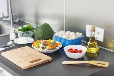 Bir masada kiraz domates, mantar, papyon renkli makarna ve yağ.