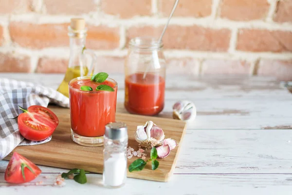 Sumo de tomate em um copo e tomates frescos na mesa de madeira . — Fotografia de Stock