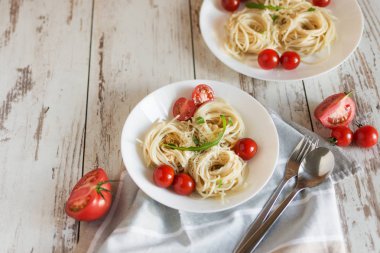 Domates, parmesan ve arugula leves ile beyaz bir porselen tabak ta İtalyan makarna spagetti yuvaları.