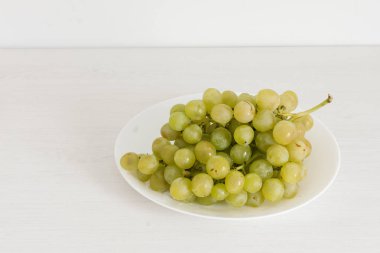Beyaz ahşap arka plan üzerinde yeşil üzüm Demet.