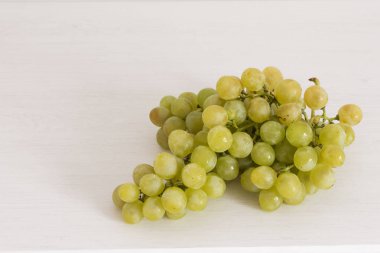 Beyaz ahşap arka plan üzerinde yeşil üzüm Demet.