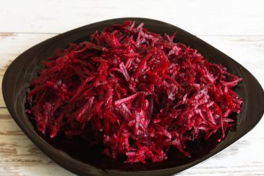 Ahşap arka planda siyah plaka üzerine rendelenmiş taze pancar.