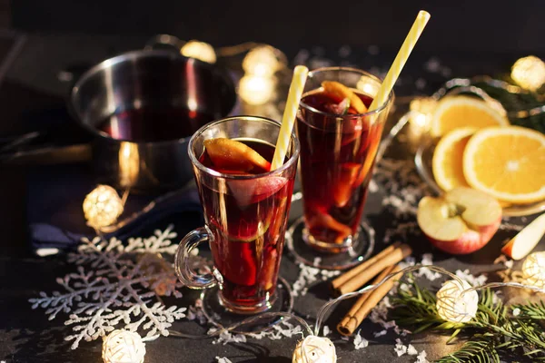Svateční víno s plátkem pomerančů, jablek a koření na vánočním pozadí s různou výzdobou. — Stock fotografie