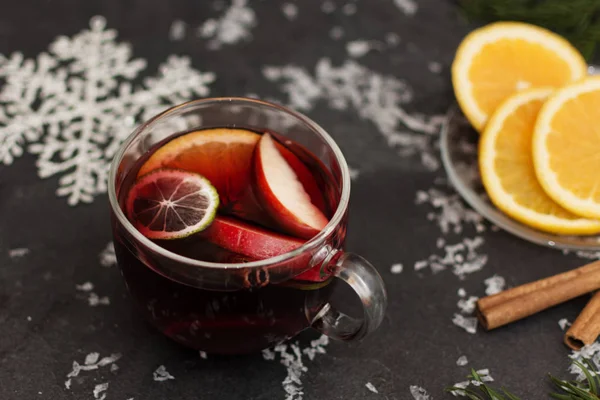 Mulled wine with slice of orange, apples and spices on christmas background with different decorations. — Stock Photo, Image